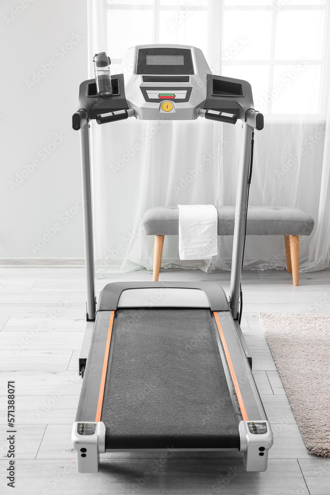 Modern treadmill in interior of light room