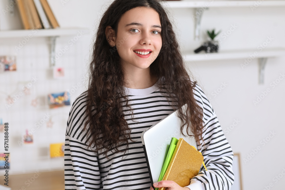 Female student with notebooks and laptop at home