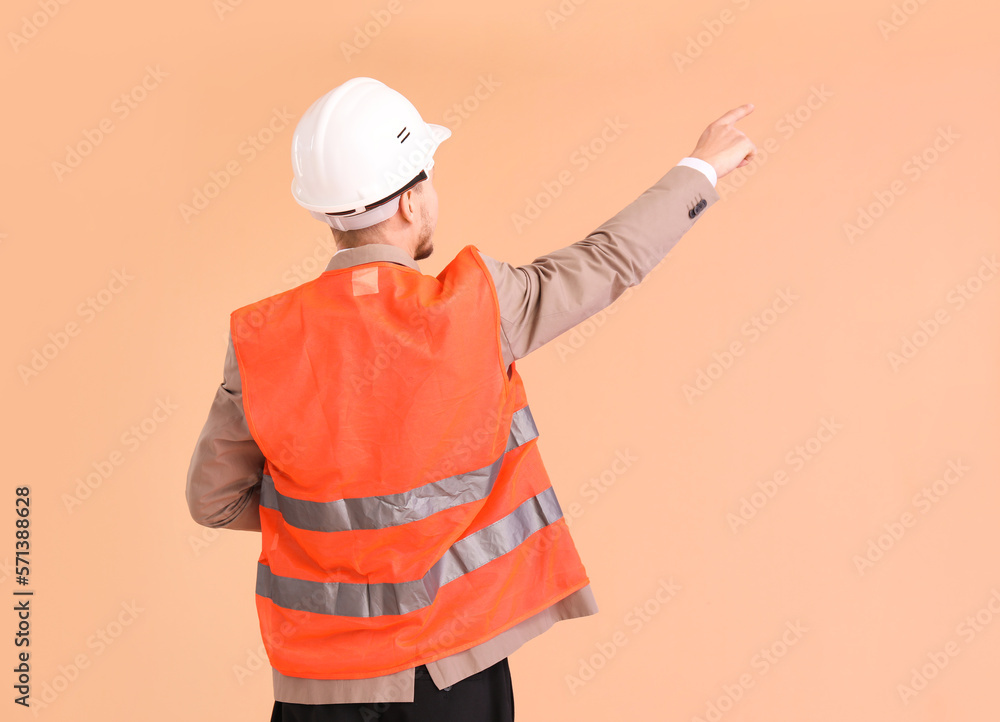 Male architect in vest pointing at something on beige background