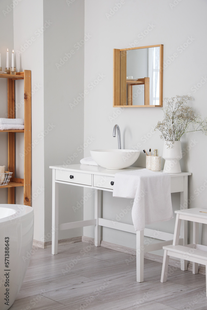 Table with sink and flowers in interior of light bathroom