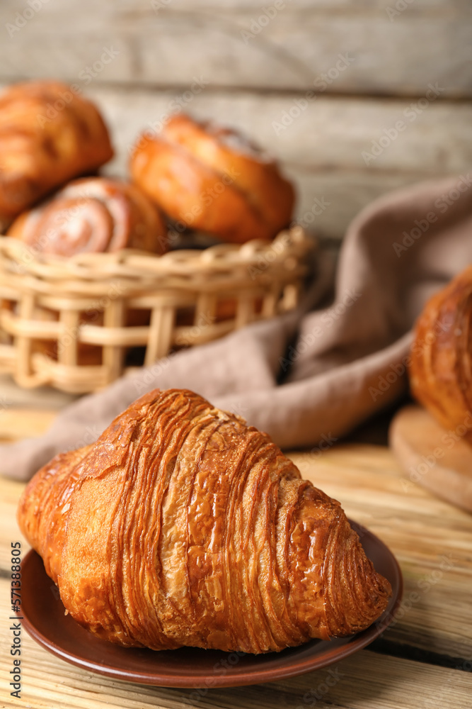 Plate with delicious croissant on wooden table