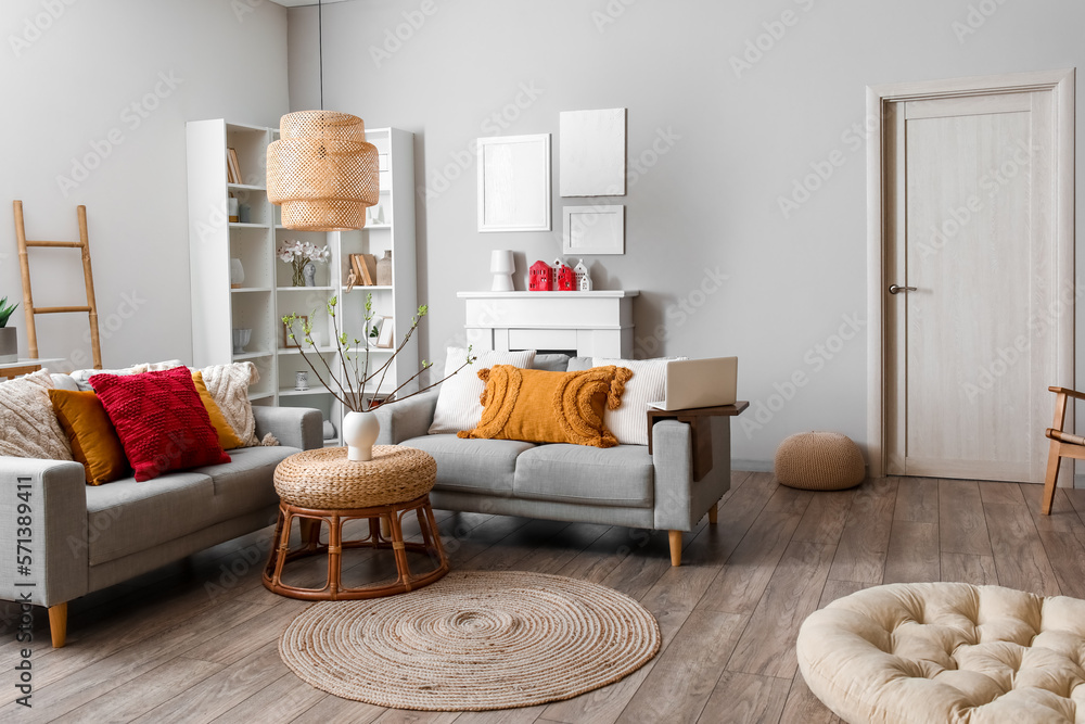 Interior of living room with sofas, houseplant and house candle holders on fireplace