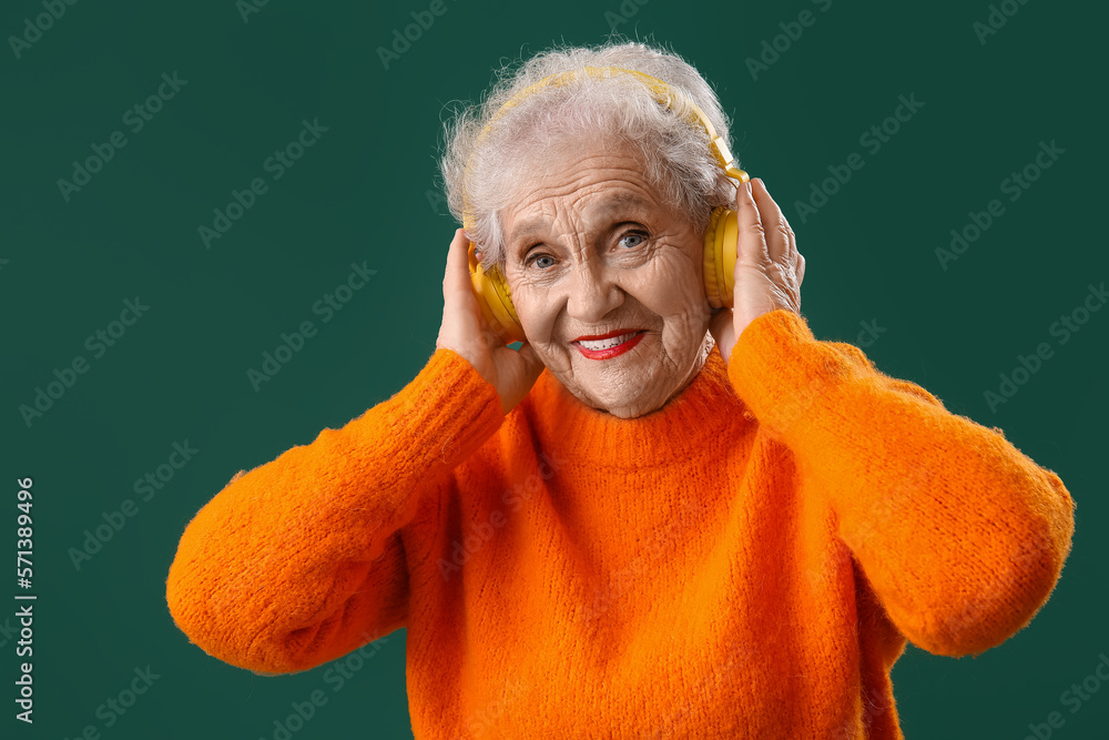 Senior woman in headphones on green background