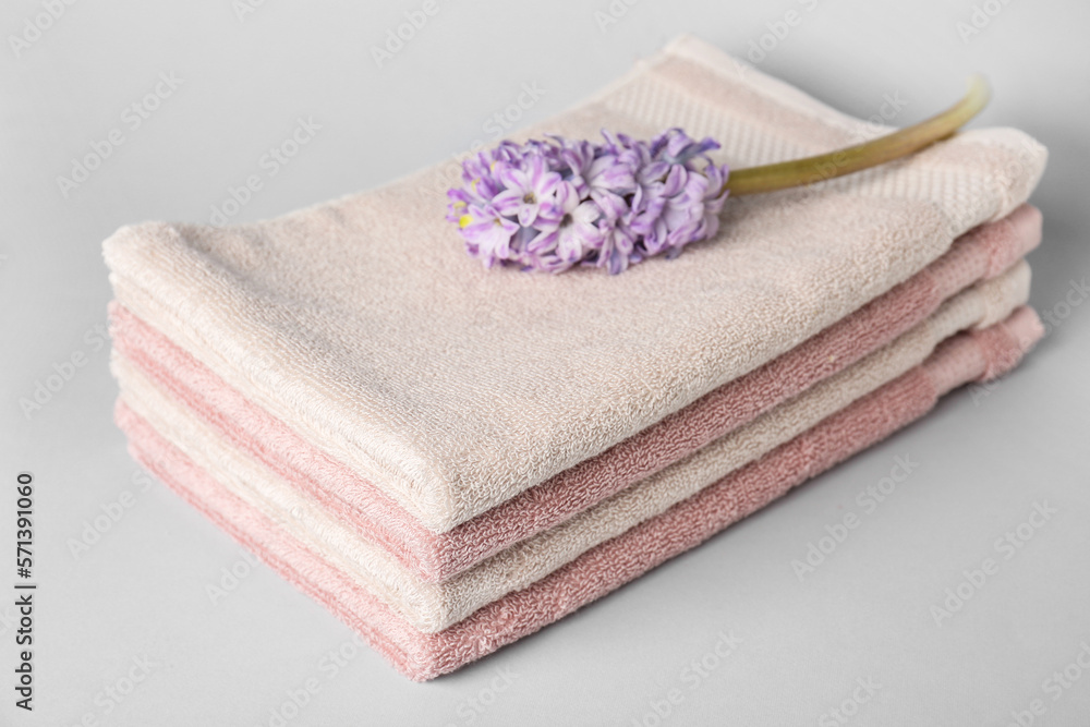 Stack of soft towels and hyacinth flower on white background