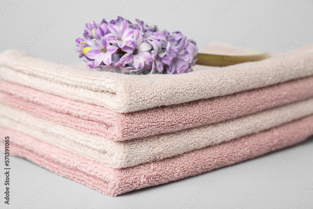 Stack of soft towels and hyacinth flower on white background, closeup