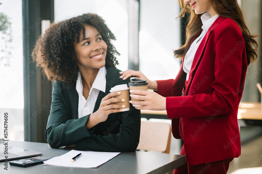 Happy two young business woman holding coffee cup in coworking office.