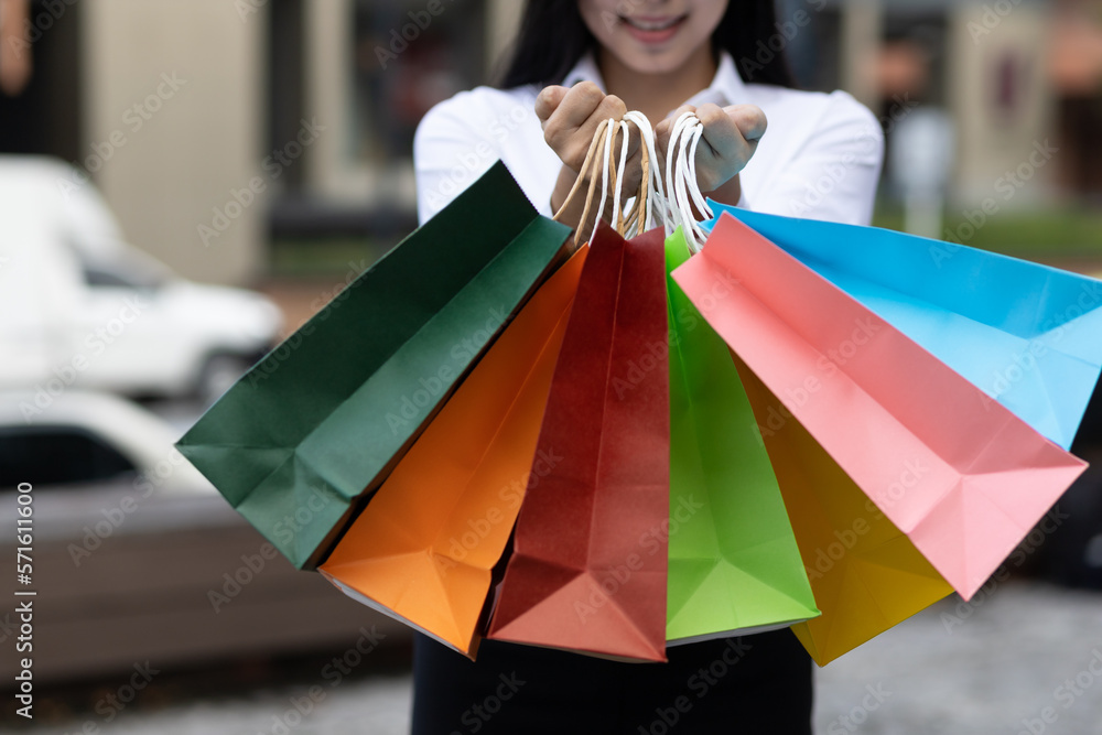 Cheerful and attractive young Asian woman carrying shopping bags. Female tourist carrying shopping b