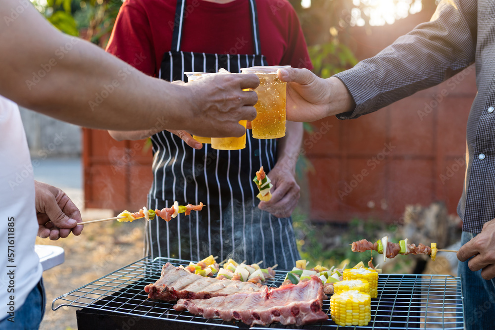 Cheers! Group of young male friends drinking beer at outdoor barbecue party at home.