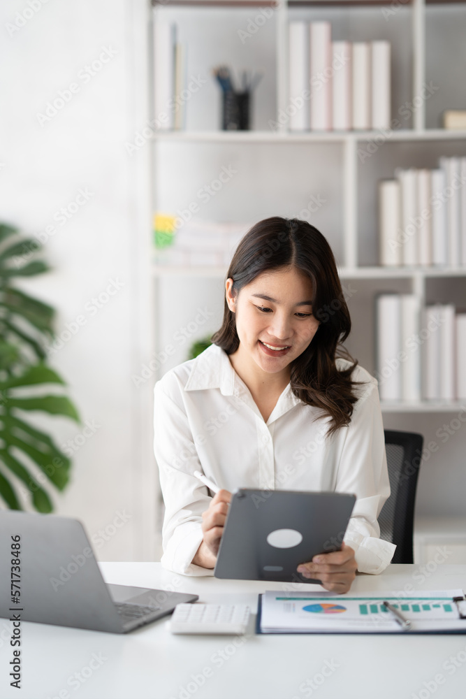 Young smart businesswoman writing her ideas on digital tablet while sitting in the modern office roo