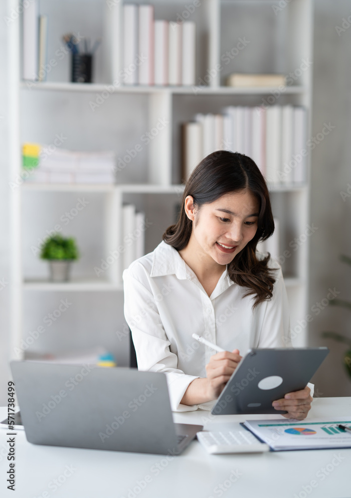 Young smart businesswoman writing her ideas on digital tablet while sitting in the modern office roo