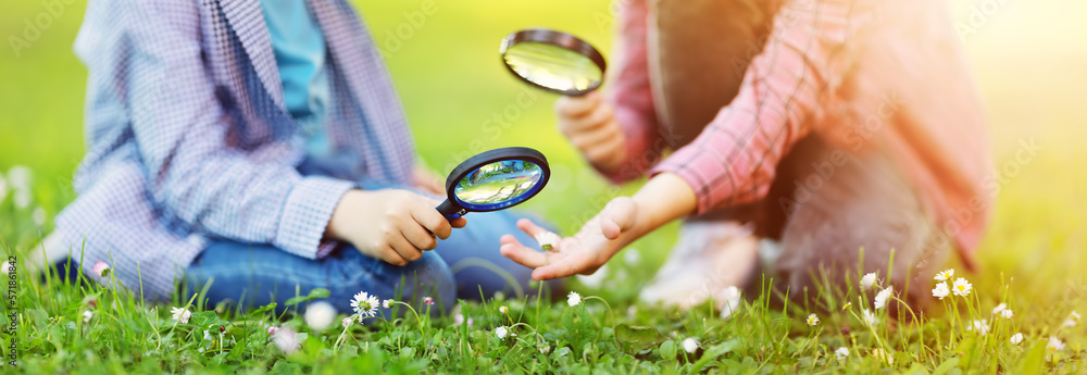 Children exploring fresh nature by using magnifying glasses.