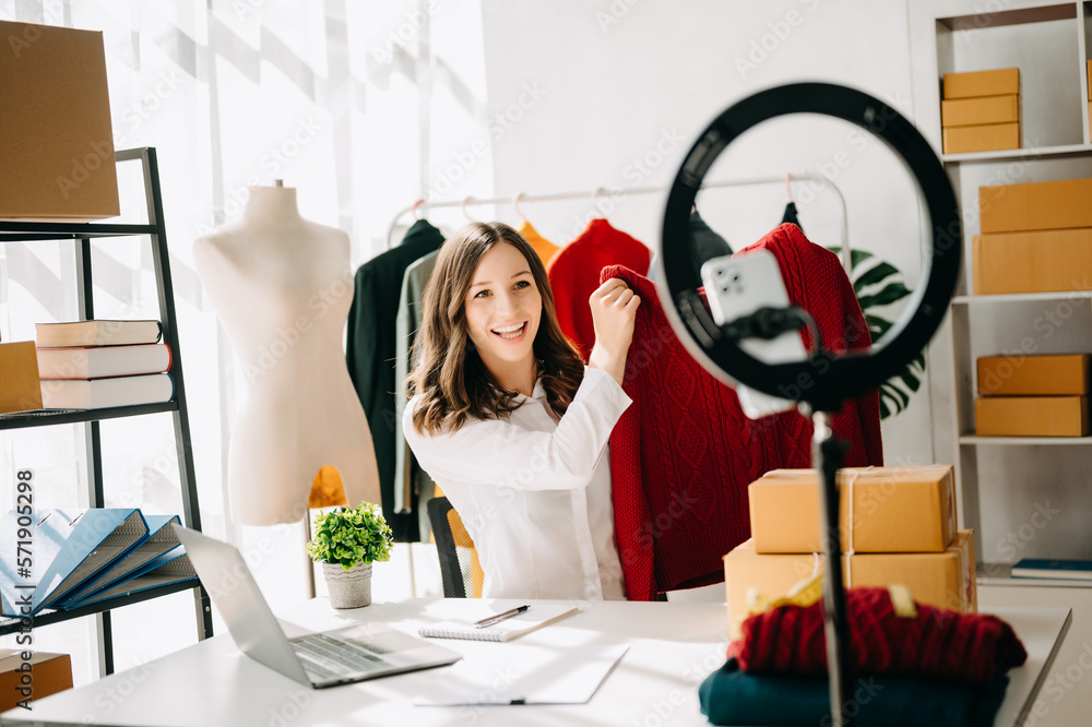 Beautiful Asian lady blogger showing clothes in front of the camera to recording vlog video live str