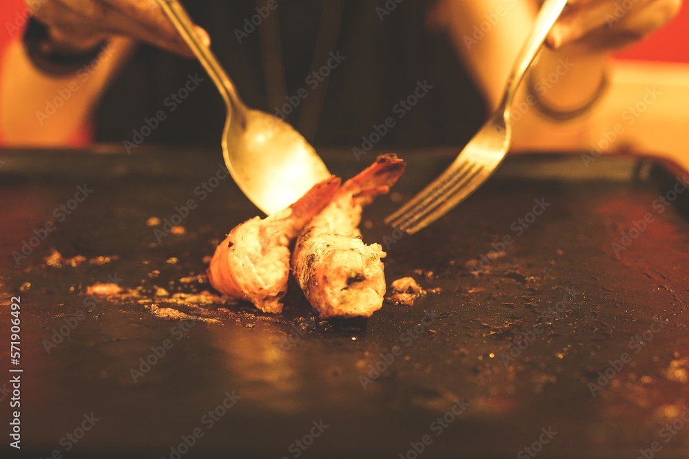 Grilled shrimp on a hot pan with spoon and fork.