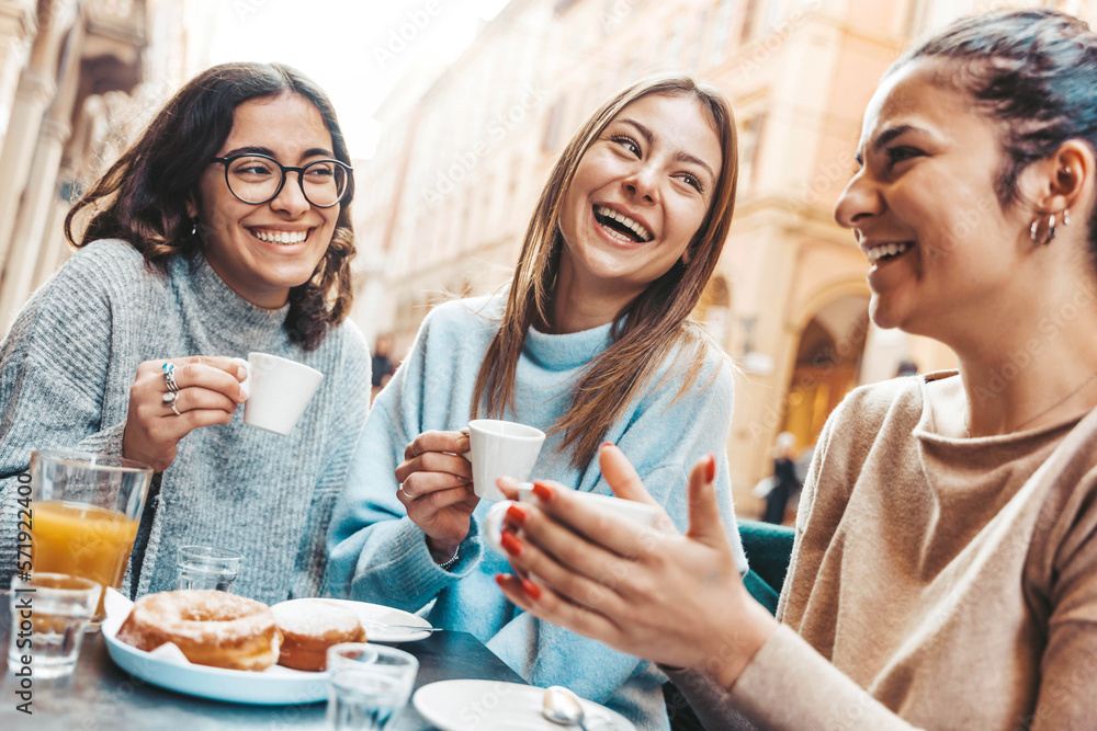 Three young women enjoying breakfast drinking coffee sitting at bar cafeteria - Life style concept w