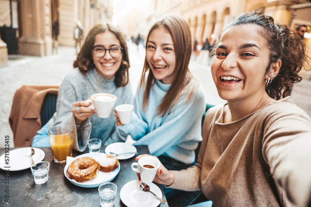 Three young women taking selfie picture drinking coffee sitting at bar cafeteria - Life style concep