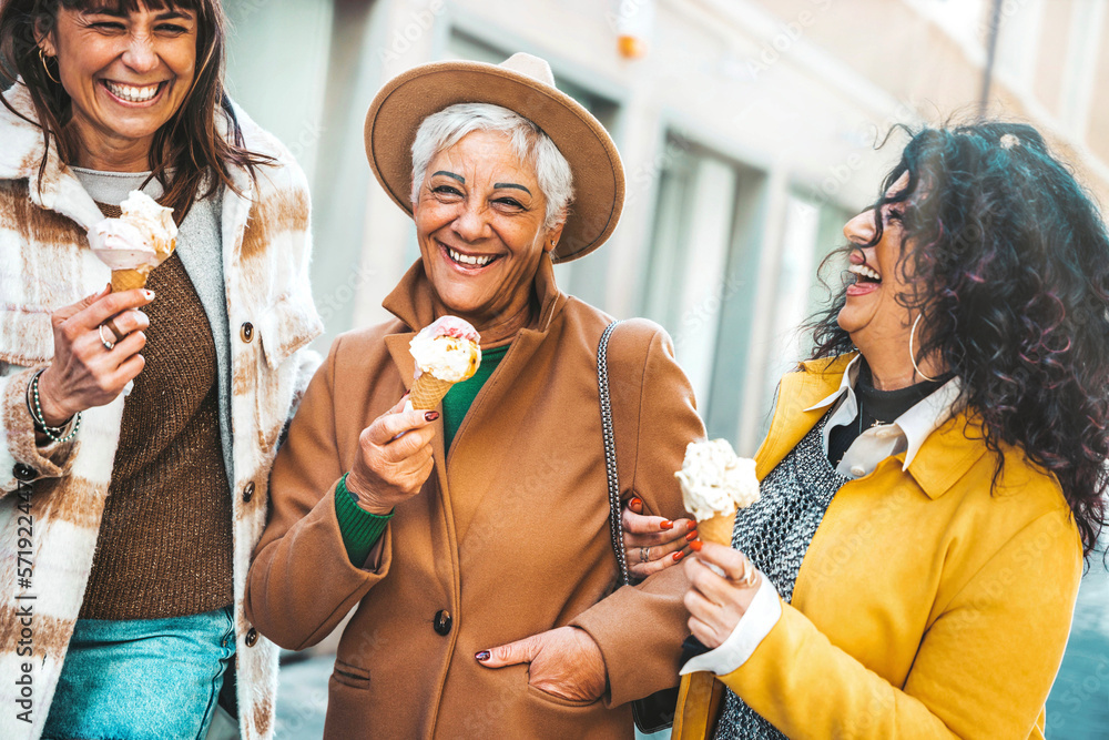 Three mature women eating ice cream cone outside - Older female friends having fun walking on city s