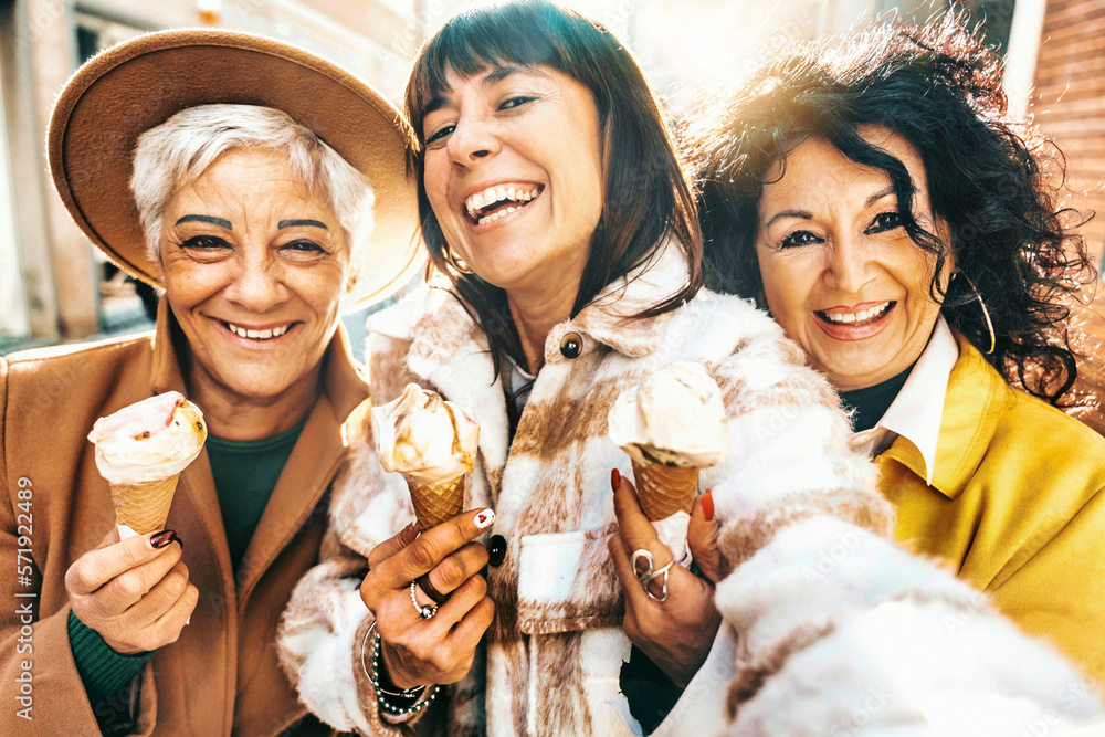 Three mature women eating ice cream cone outside - Older female friends having fun walking on city s