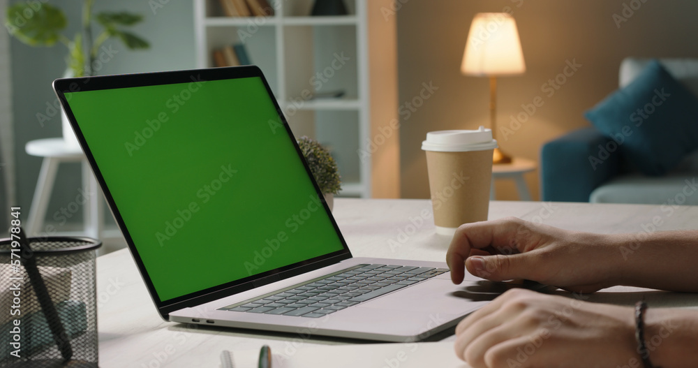 Close up shot of hands of freelancer working with chroma key green screen laptop, using trackpad scr