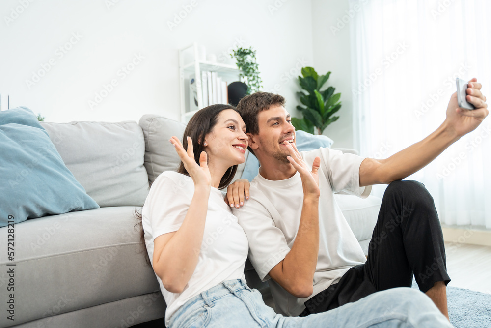 Caucasian attractive couple use mobile phone video call in living room