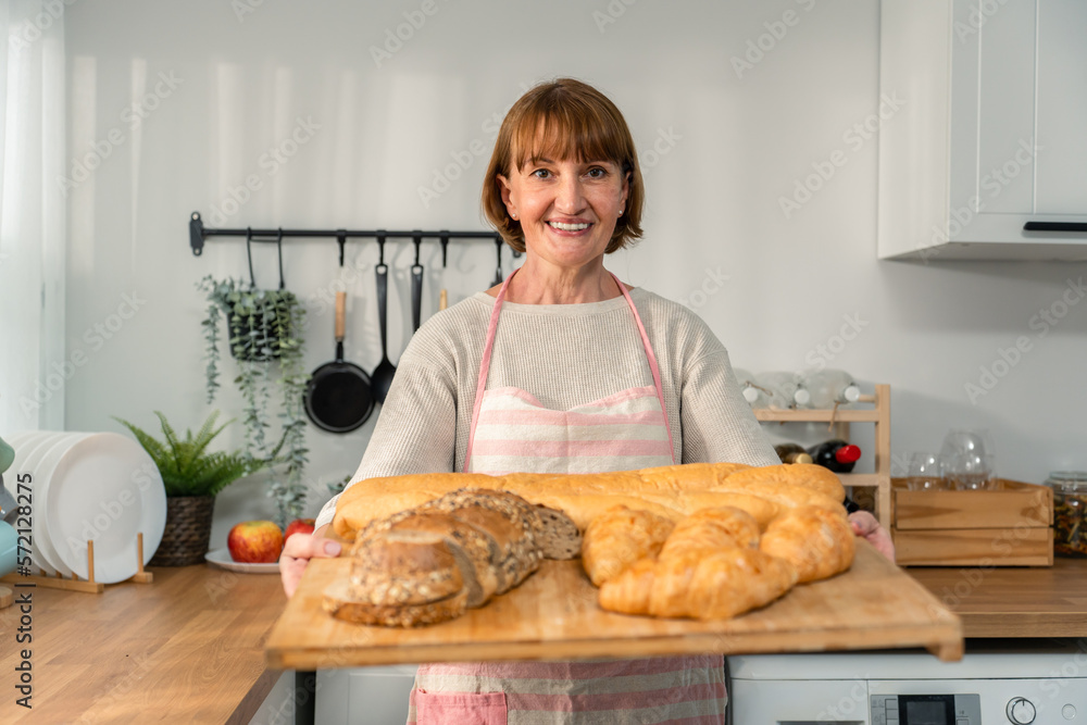 Portrait of Caucasian senior woman hold bowl of bread, look at camera. 