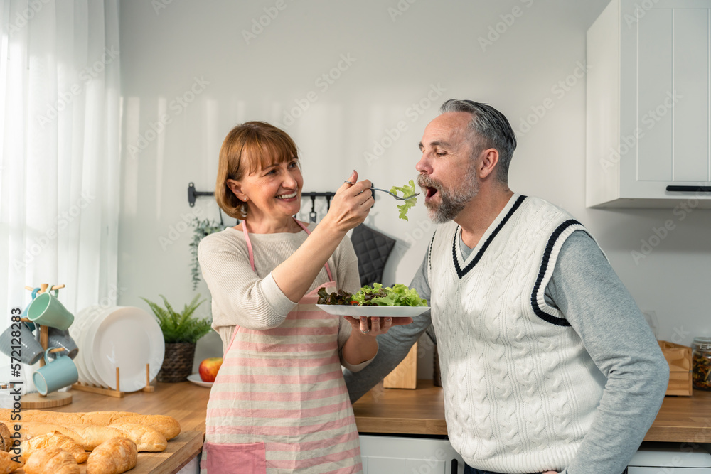 Caucasian senior elderly couple spend time together in kitchen at home