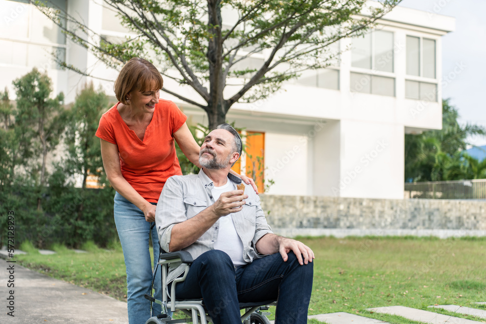 Caucasian senior woman support husband on wheelchair outdoor in garden