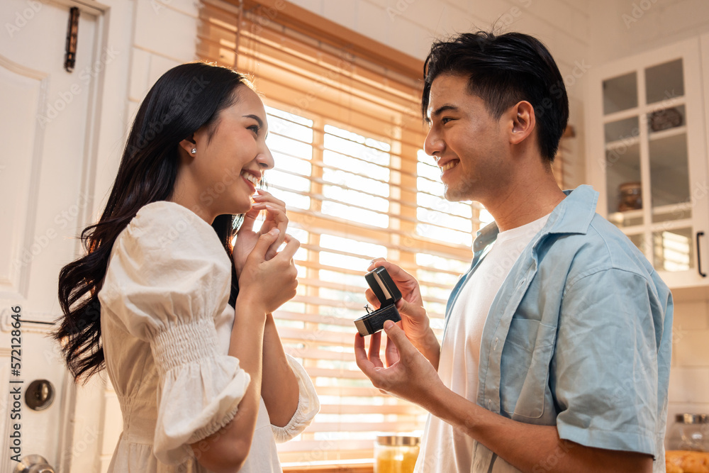 Asian romantic man making surprise proposal of marriage to girlfriend. 