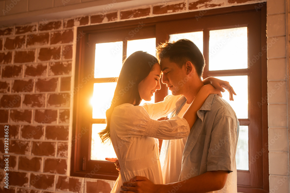 Asian young man and woman kissing each other in living room at home. 