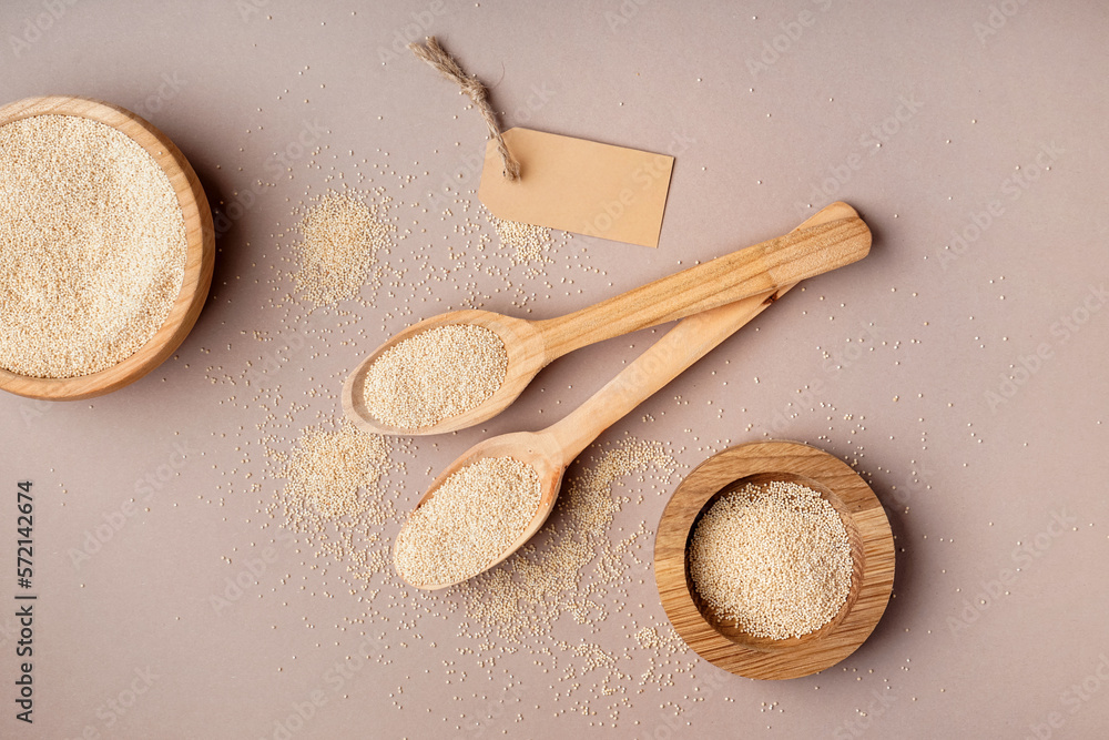 Composition with wooden spoons and bowls of amaranth seeds on color background