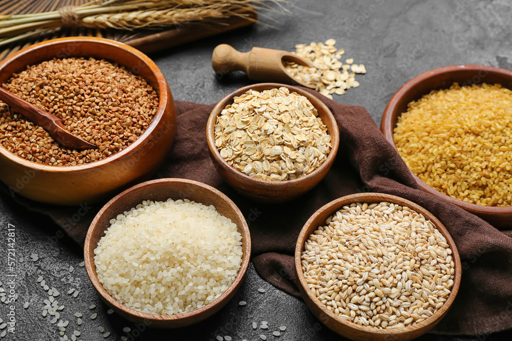 Bowls with different cereals on dark background