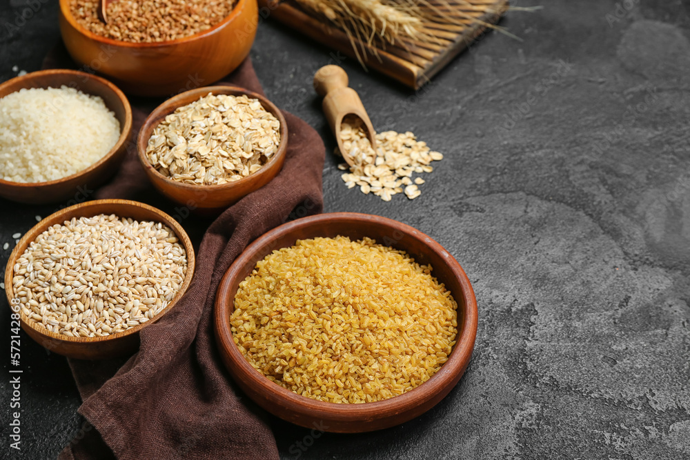 Bowls with different cereals on dark background