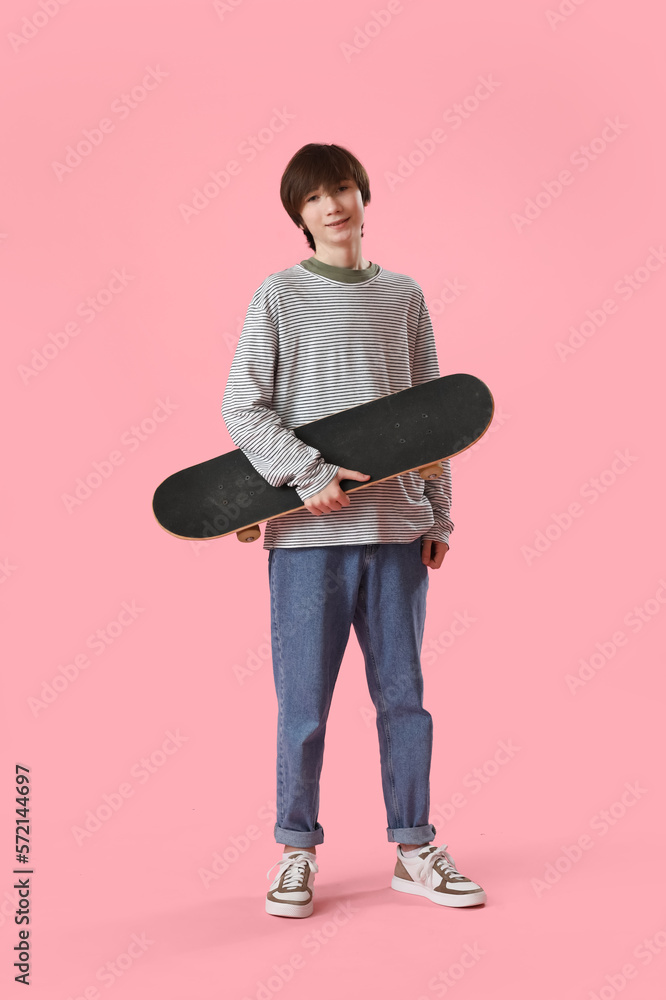 Teenage boy with skateboard on pink background