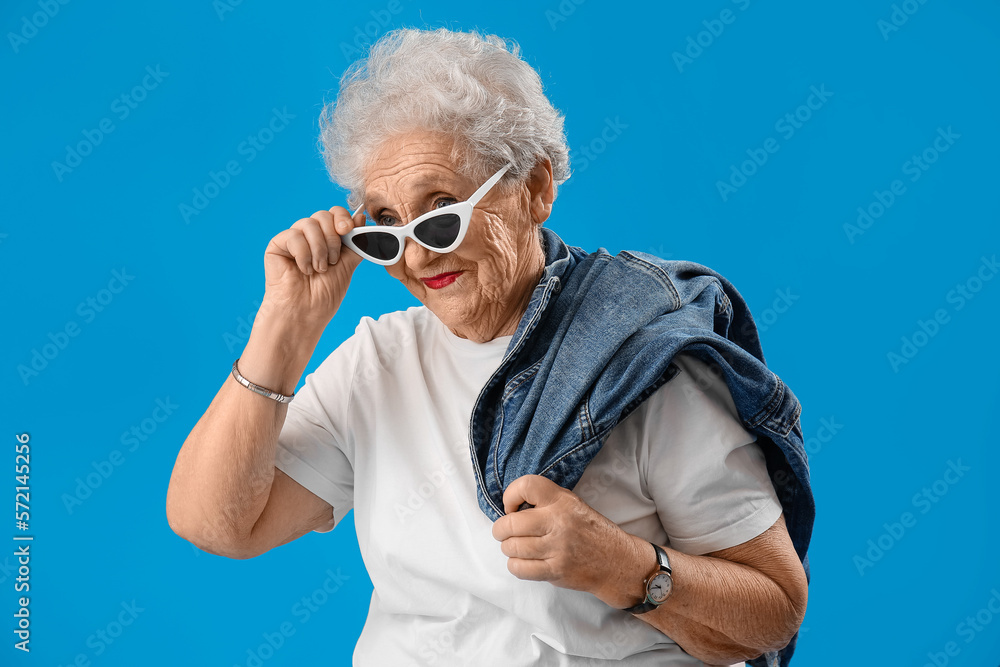 Senior woman in sunglasses on blue background