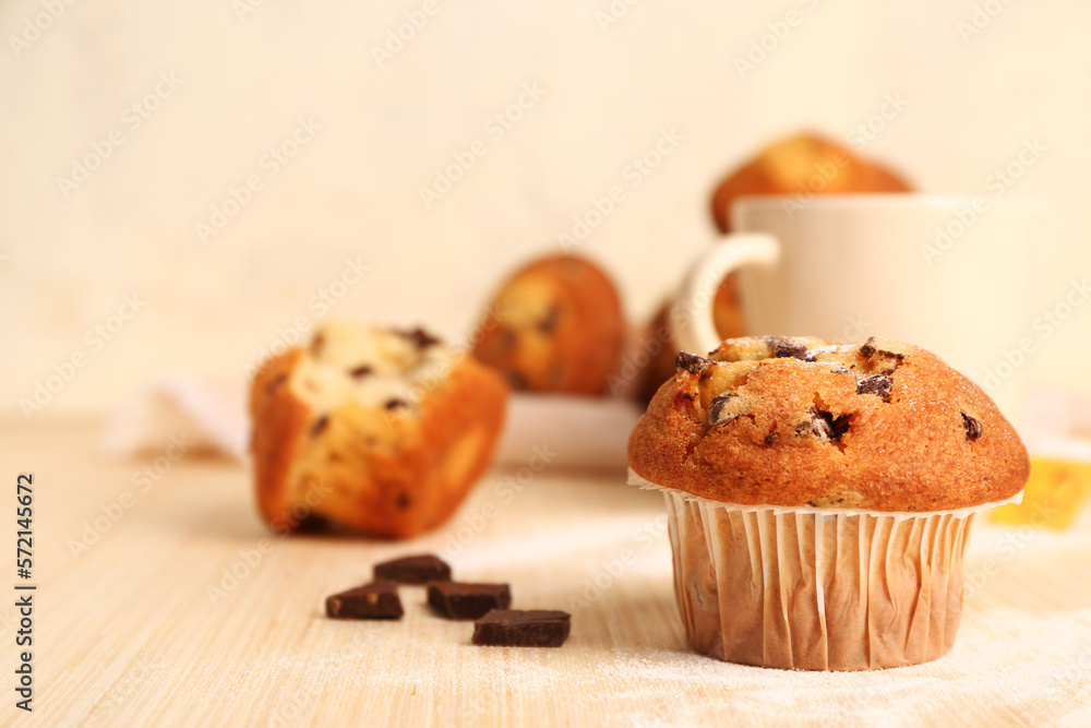 Delicious muffin with chocolate on beige wooden table