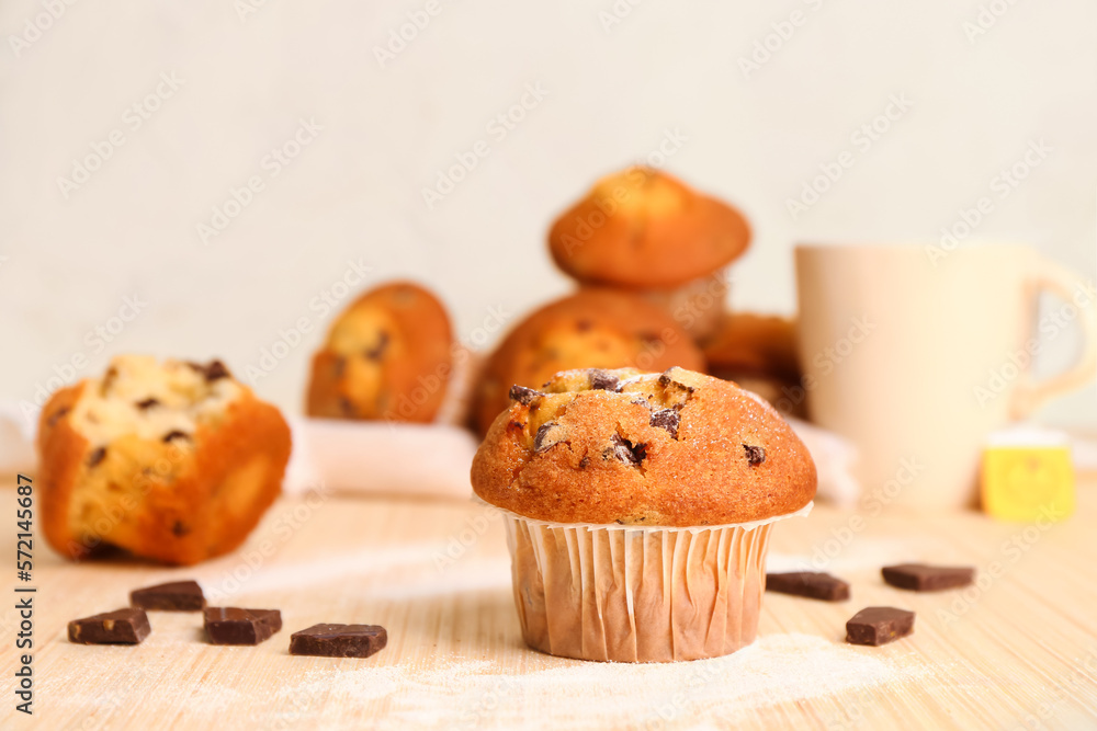 Delicious muffin with chocolate on beige wooden table