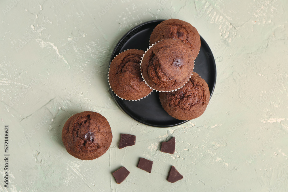 Plate with tasty chocolate muffins on light background