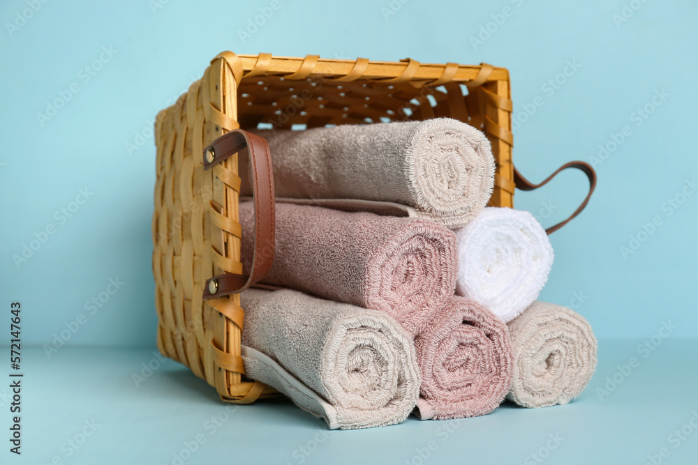 Basket with rolled clean rolled towels on color background