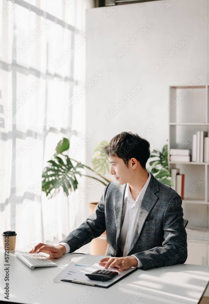 Young business man working at office with laptop, tablet and taking notes on the paper.