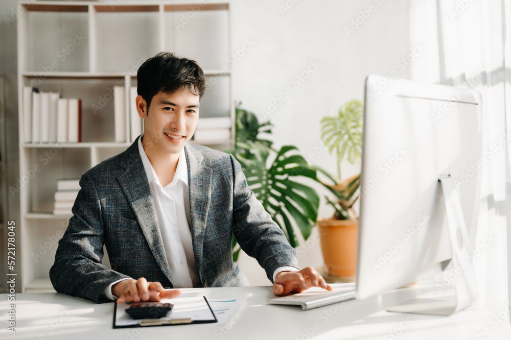 Young business man working at office with laptop, tablet and taking notes on the paper.