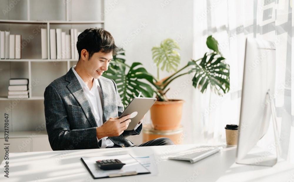 Young business man working at office with laptop, tablet and taking notes on the paper.