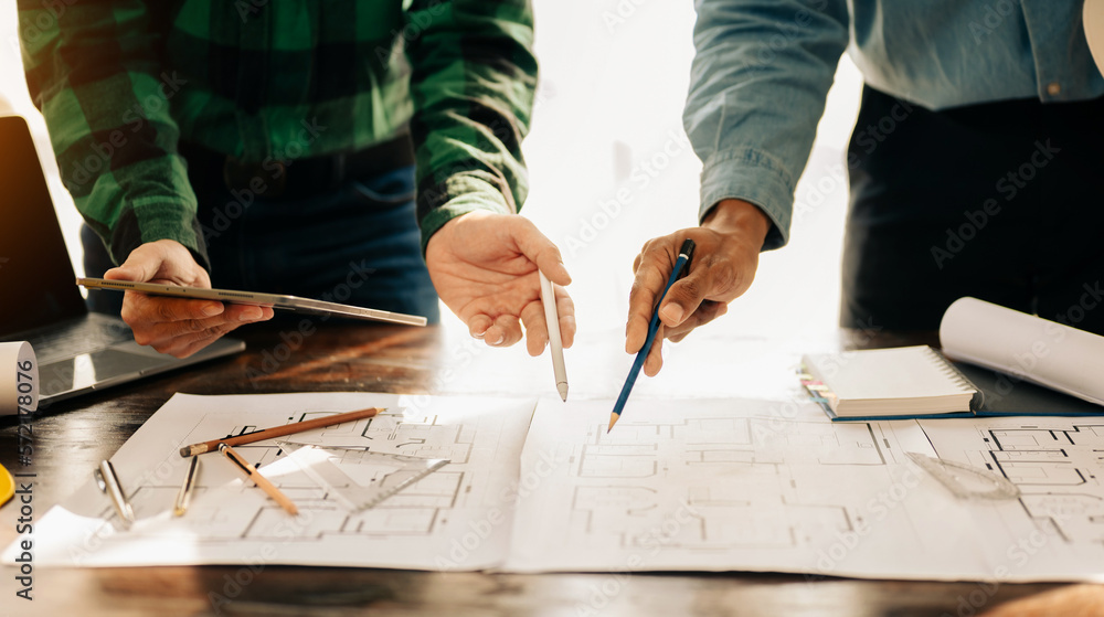 Creative architect projecting on the big drawings in the dark loft office or cafe in sun light.