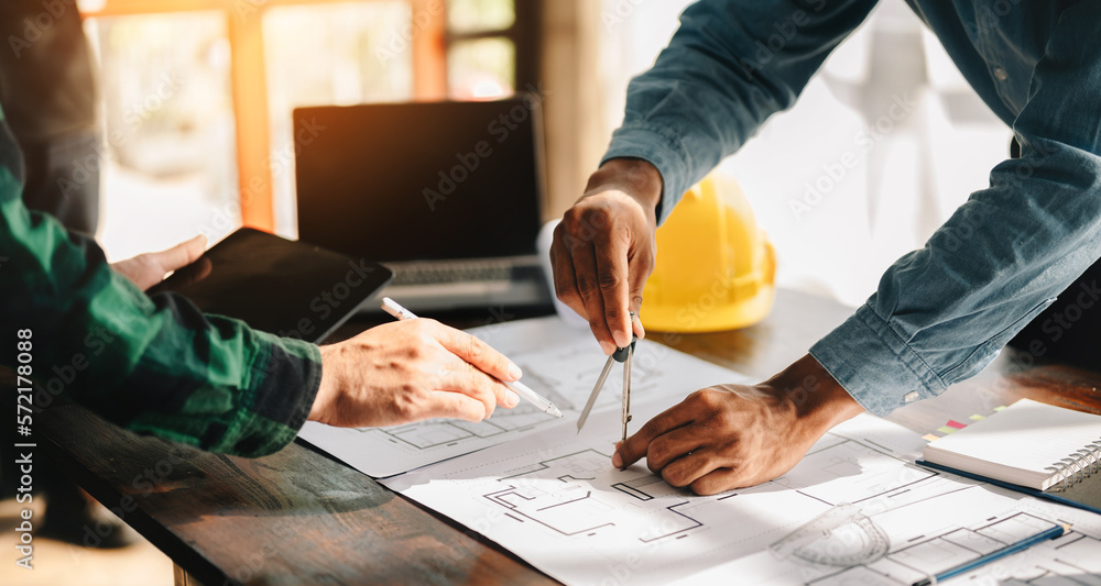 Creative architect projecting on the big drawings in the dark loft office or cafe in sun light.