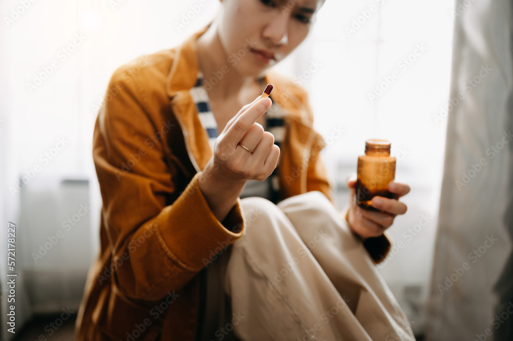  woman sit Depression Dark haired  pensive glance Standing with glass of water and pills by window a