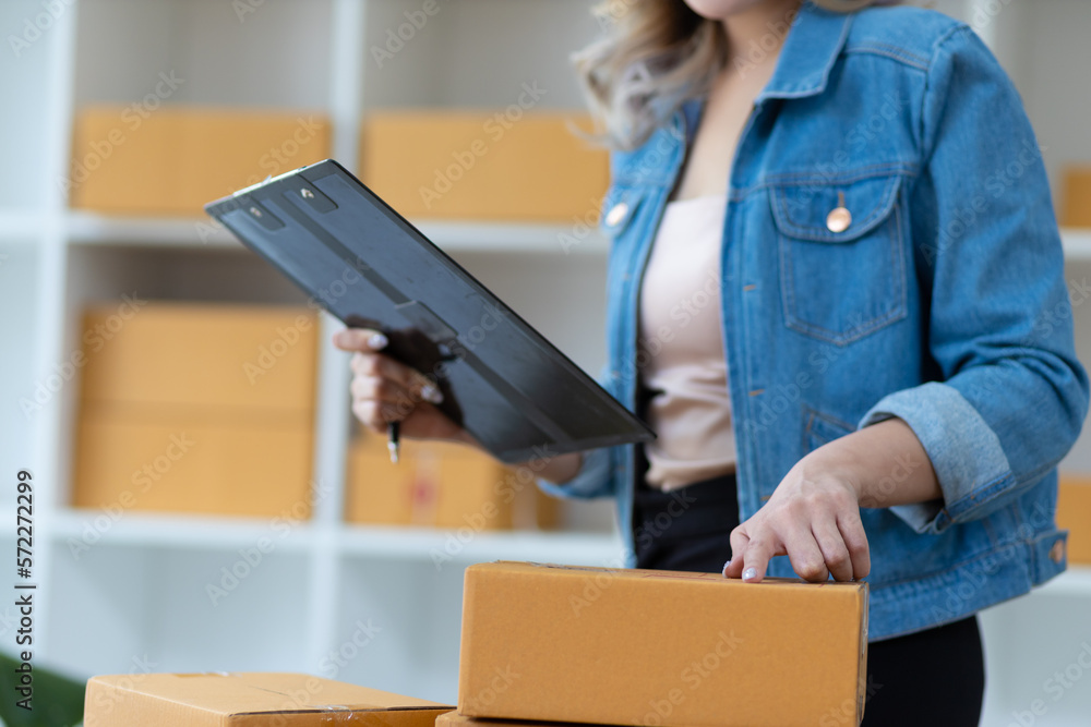 Woman who start up small business works in a warehouse. Start-up entrepreneur is writing a note on a