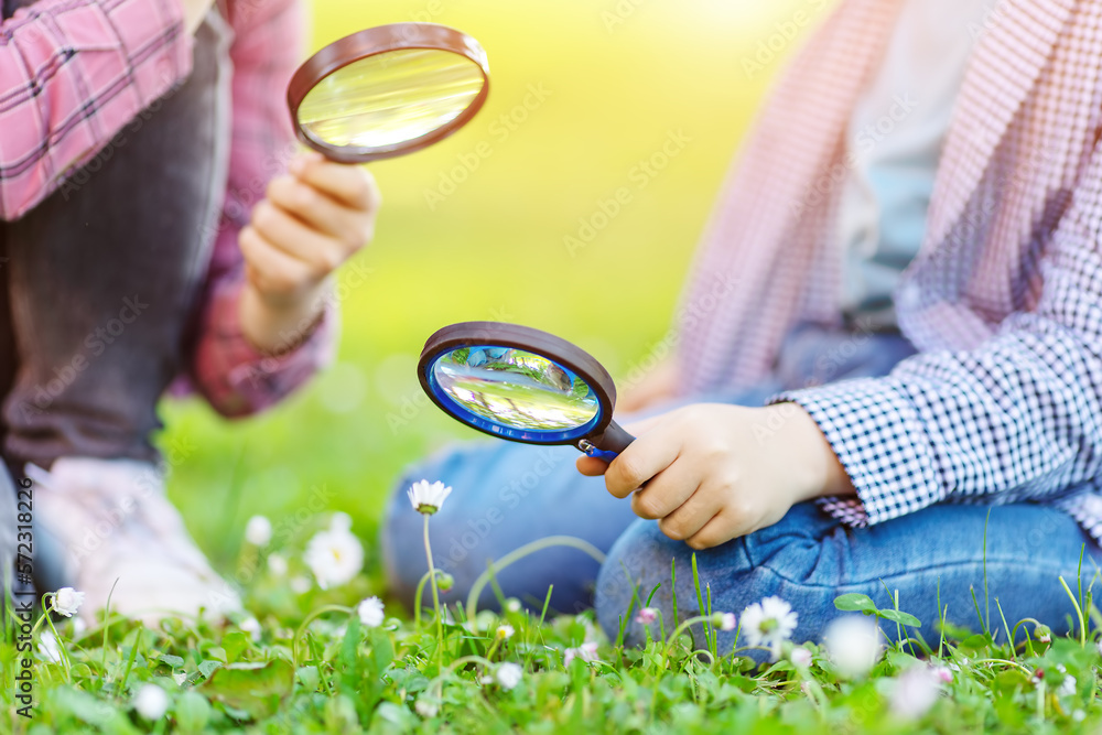 Children exploring fresh nature by using magnifying glasses.