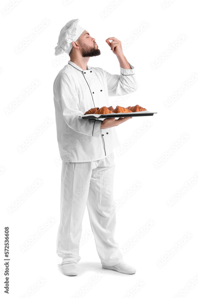 Male baker with tray of tasty croissants on white background