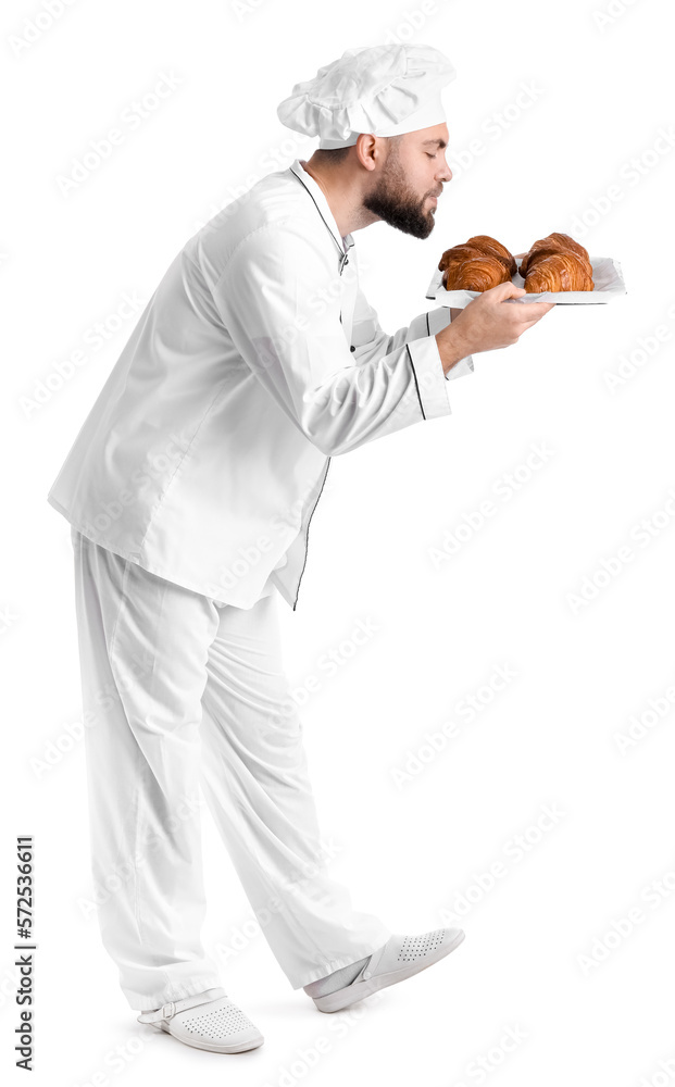 Male baker with tray of tasty croissants on white background