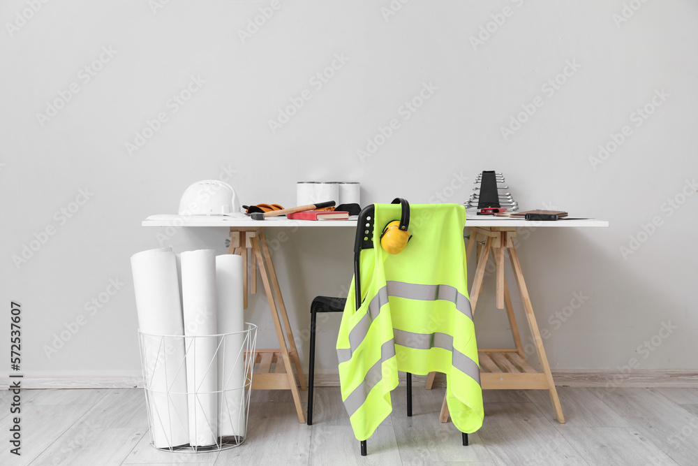 Chair and table with builders supplies near light wall