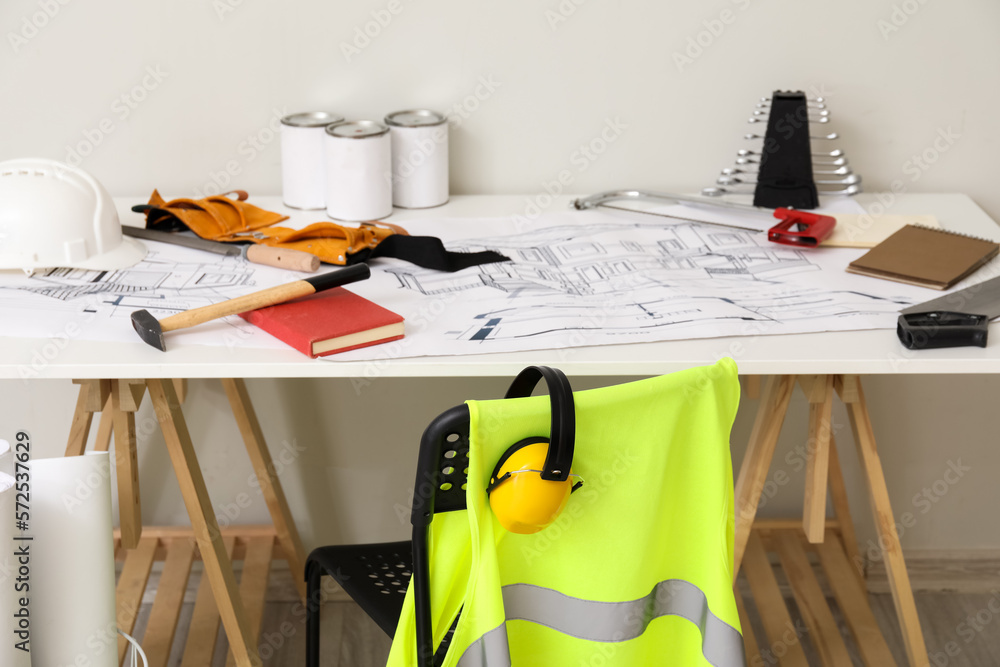 Chair and table with builders supplies near light wall