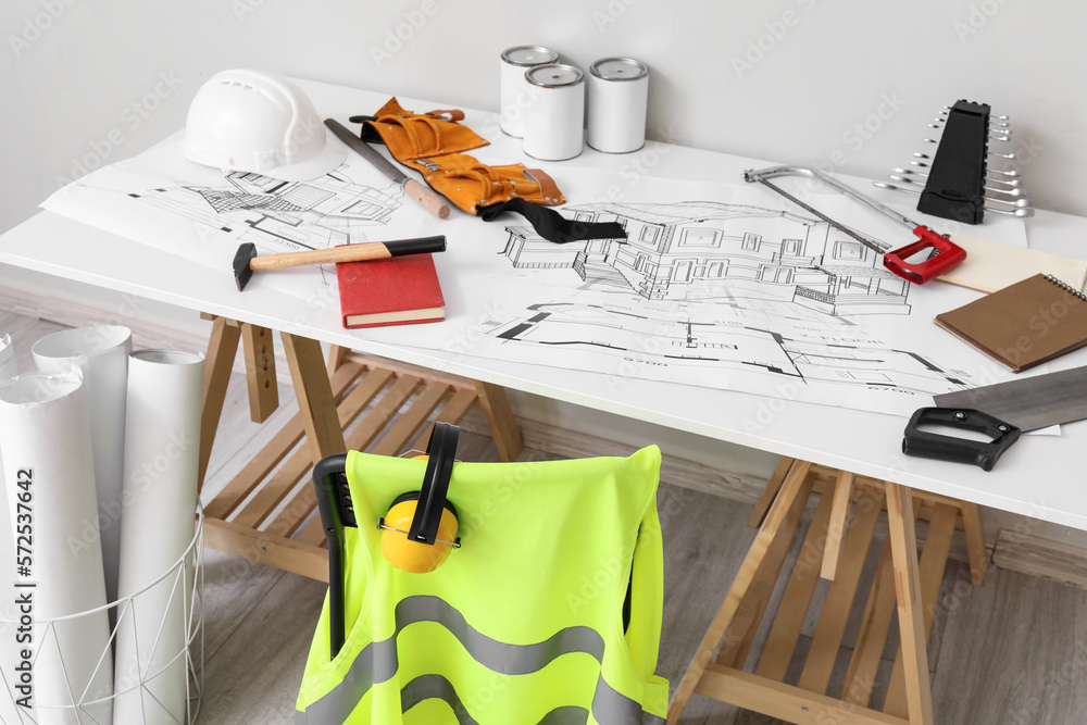 Chair and table with builders supplies near light wall